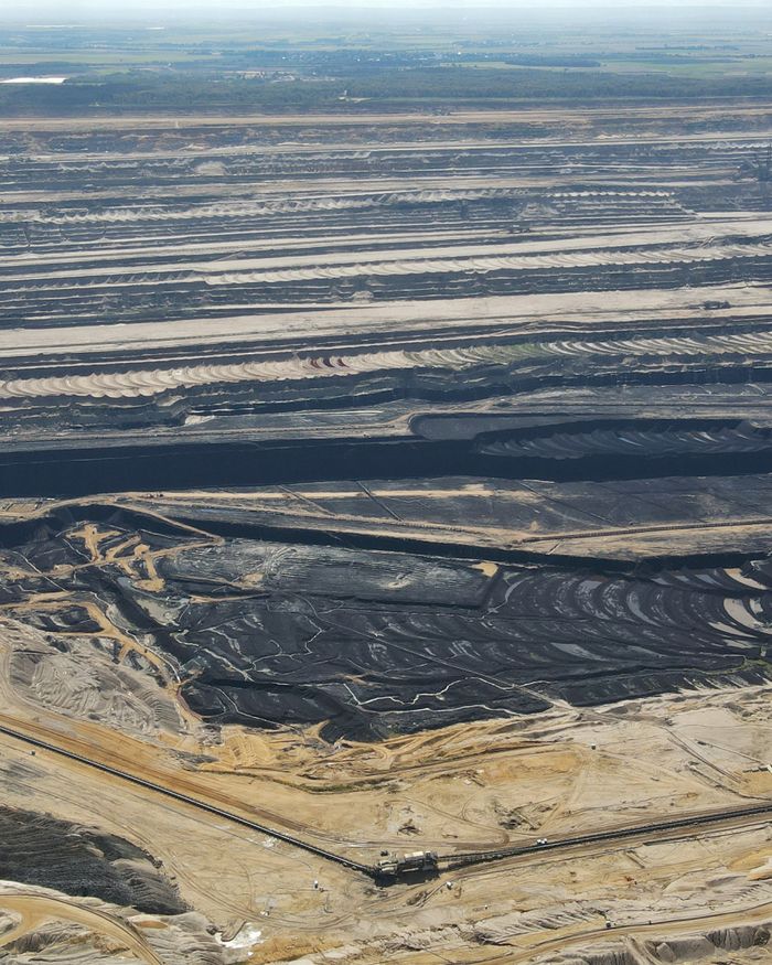 Aerial photograph showcasing a large coal mining site with layered excavations and surrounding landscapes.